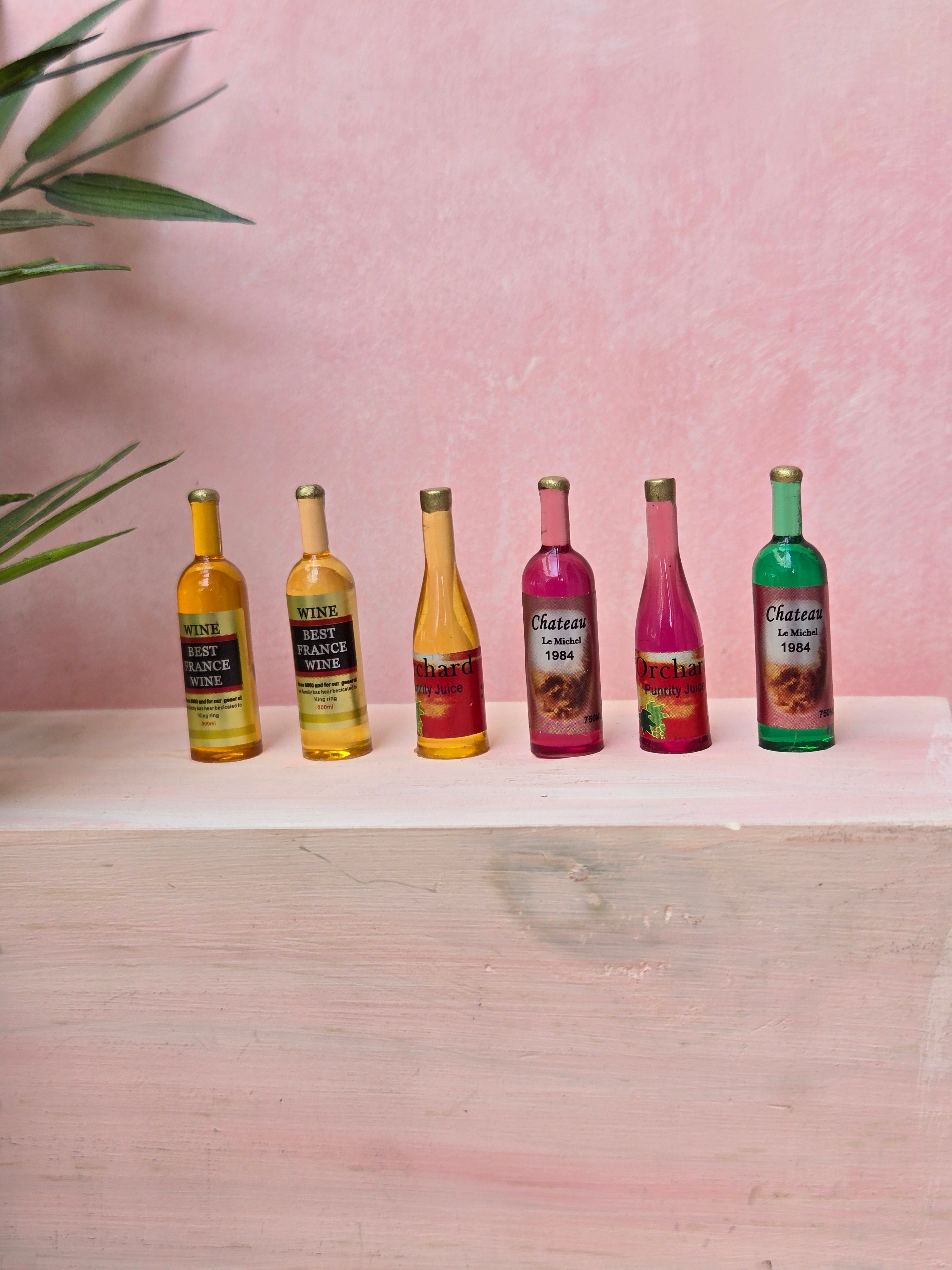 Six small bottles of Chateau 1904 wine on a white surface with a pink background