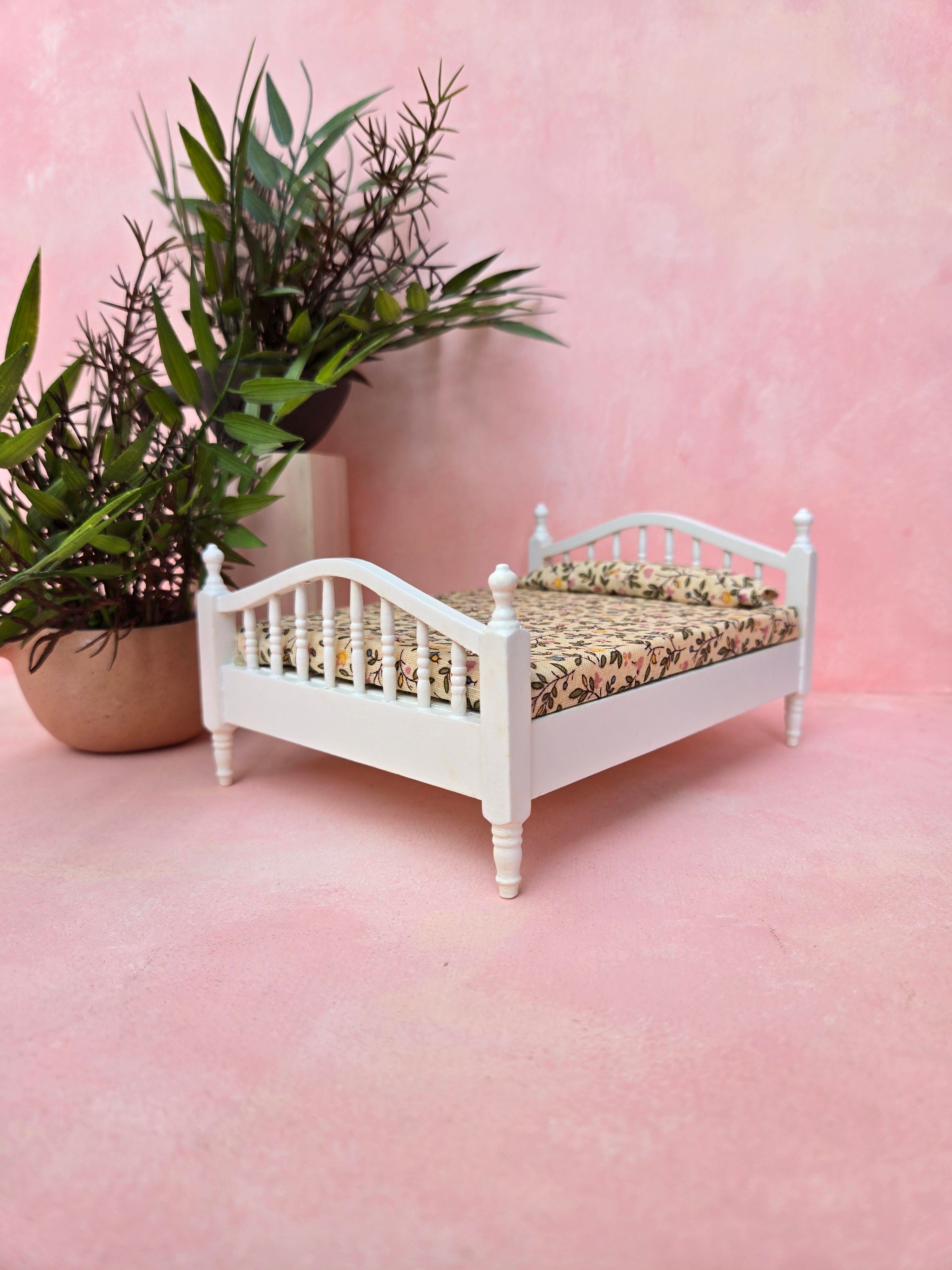 Small white bed with floral bedding on a pink floor and wall