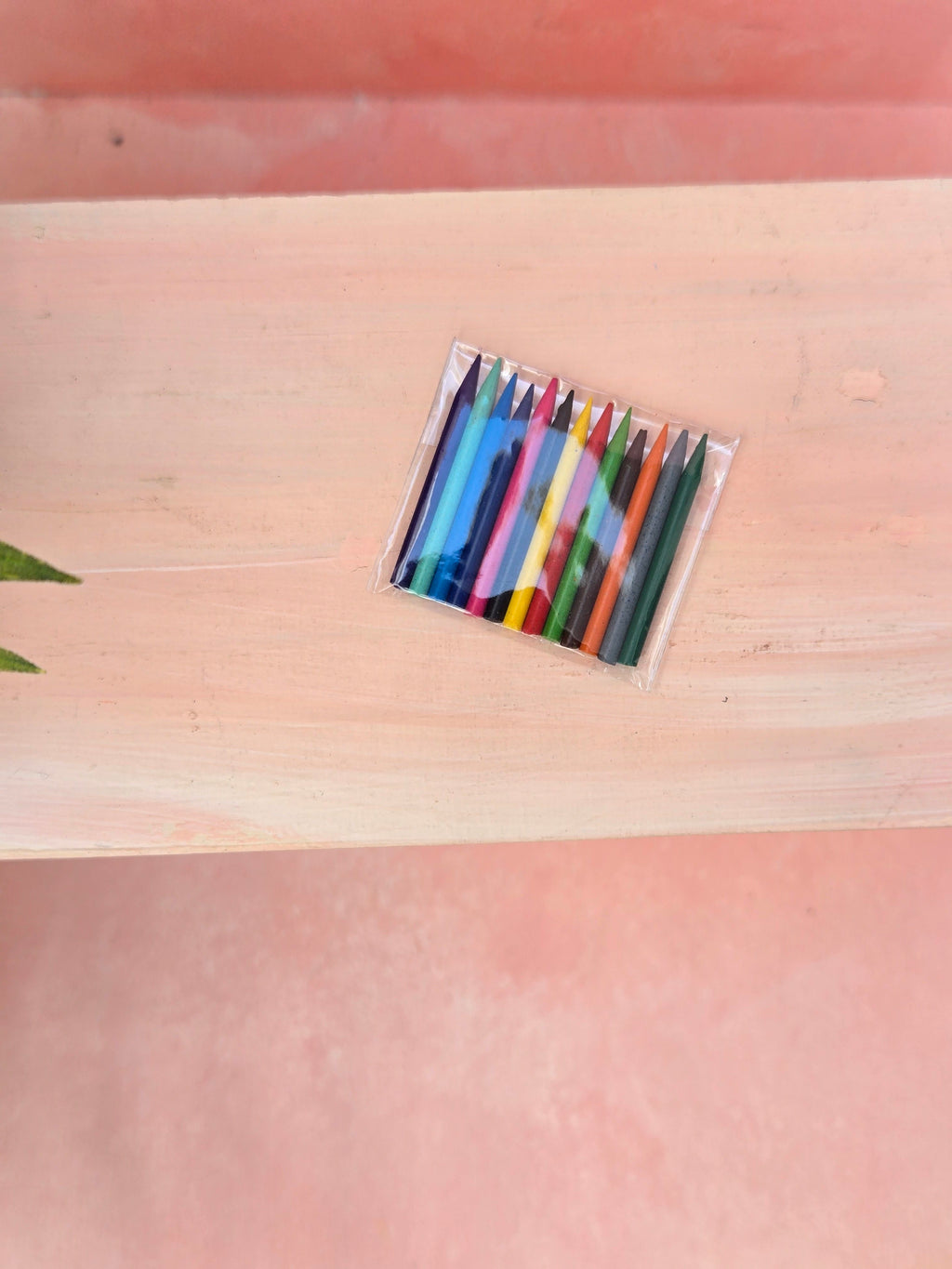 Set of colorful crayons in a clear plastic case on a wooden surface