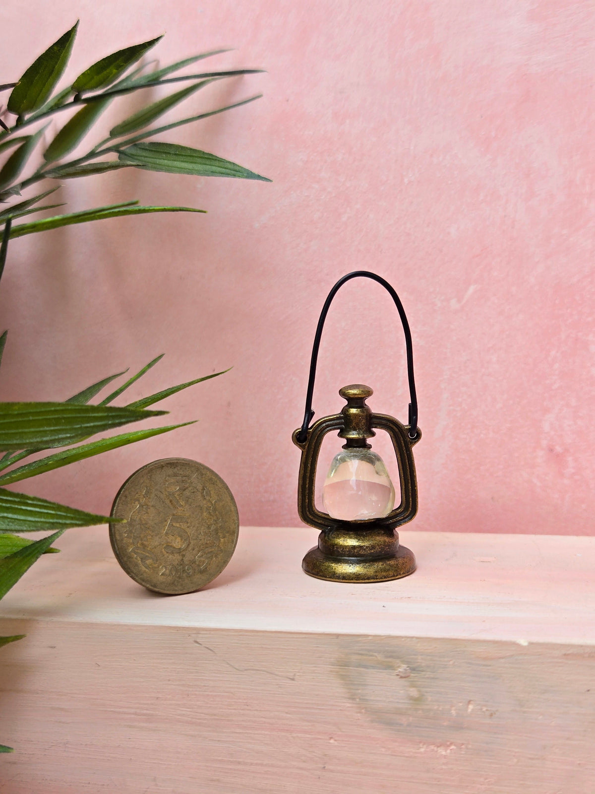 Vintage-style lantern and round object on a light surface with a pink background