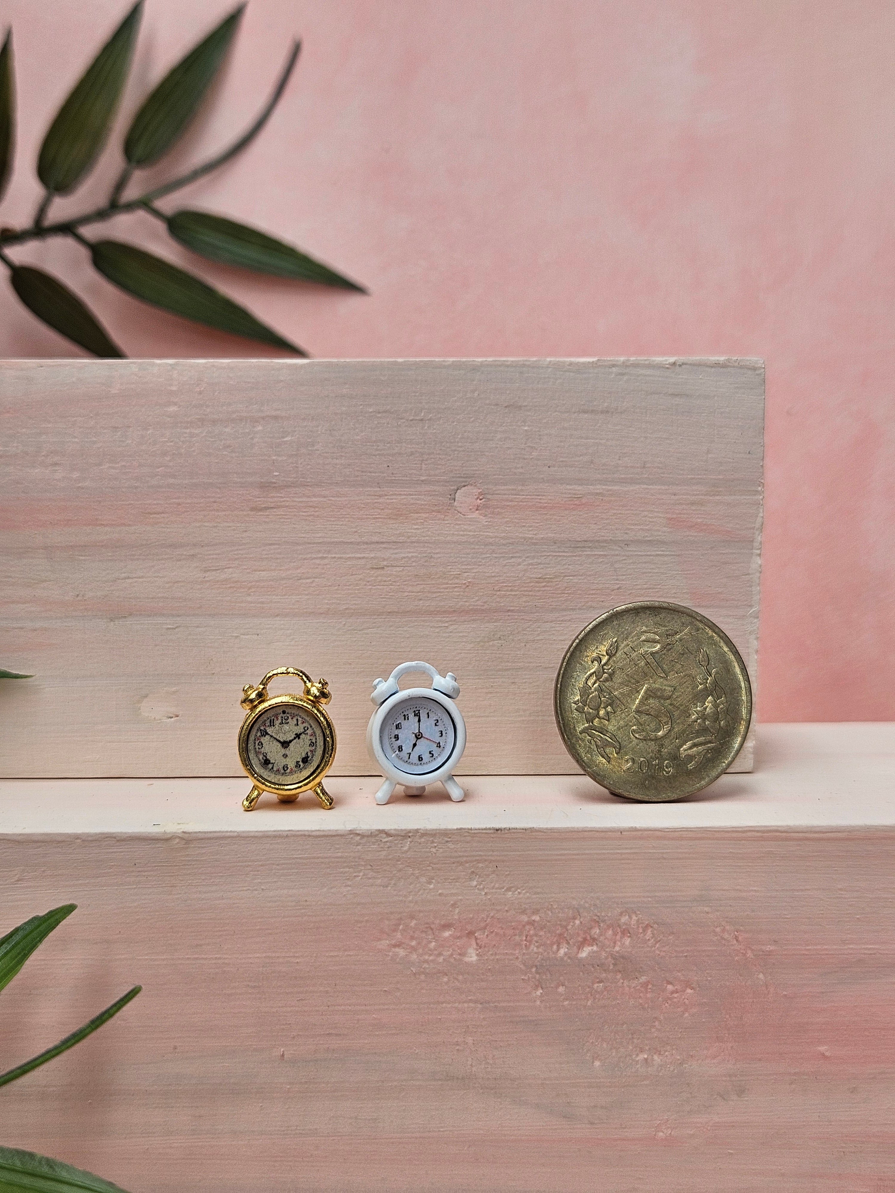 Miniature white and gold alarm clock with realistic vintage design for dollhouse décor and collectibles.